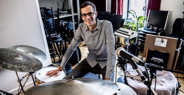 Matt Slocum smiling and sitting at his drum set.