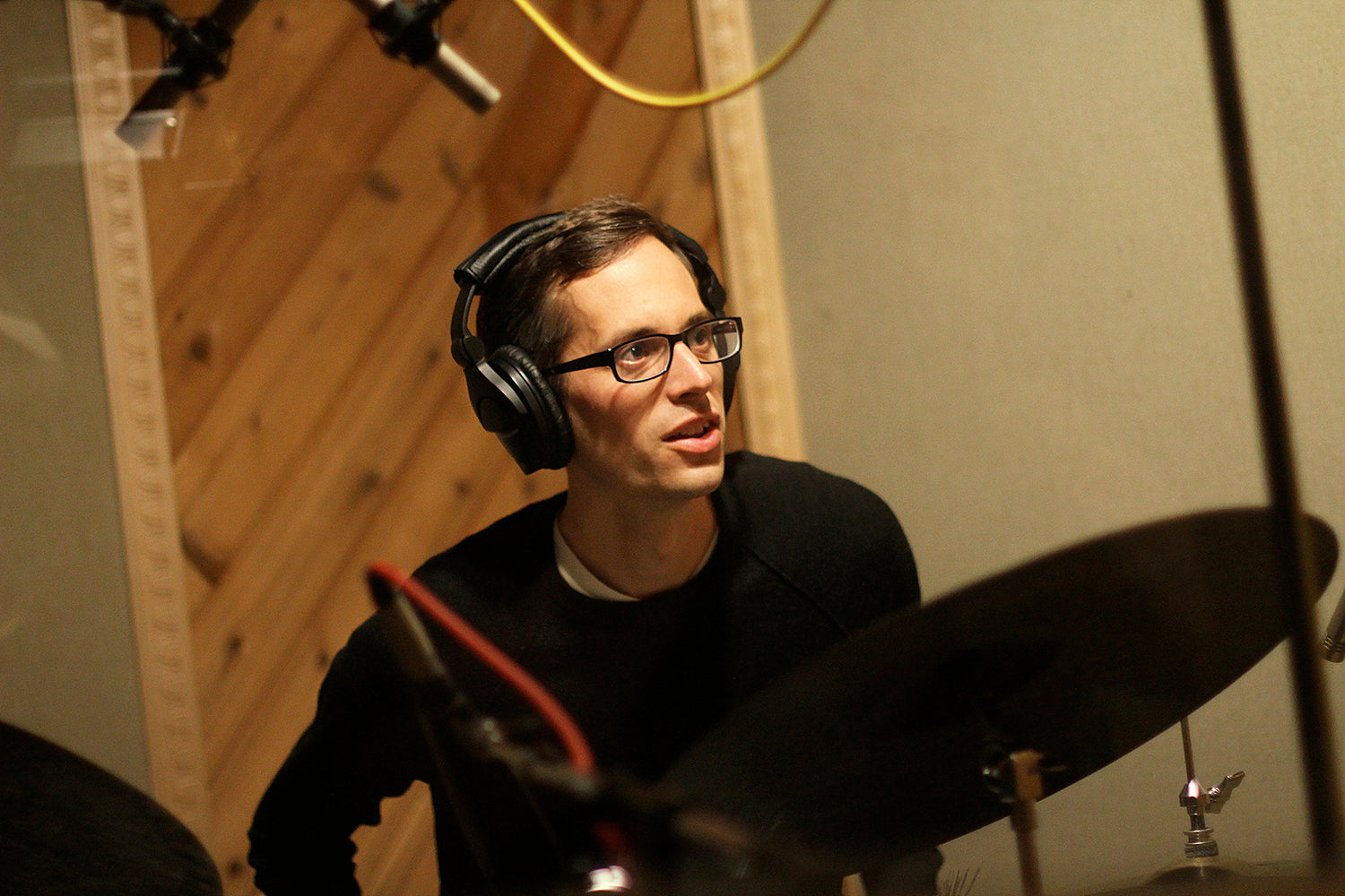 Matt Slocum playing drums with studio headphones while teaching a student
