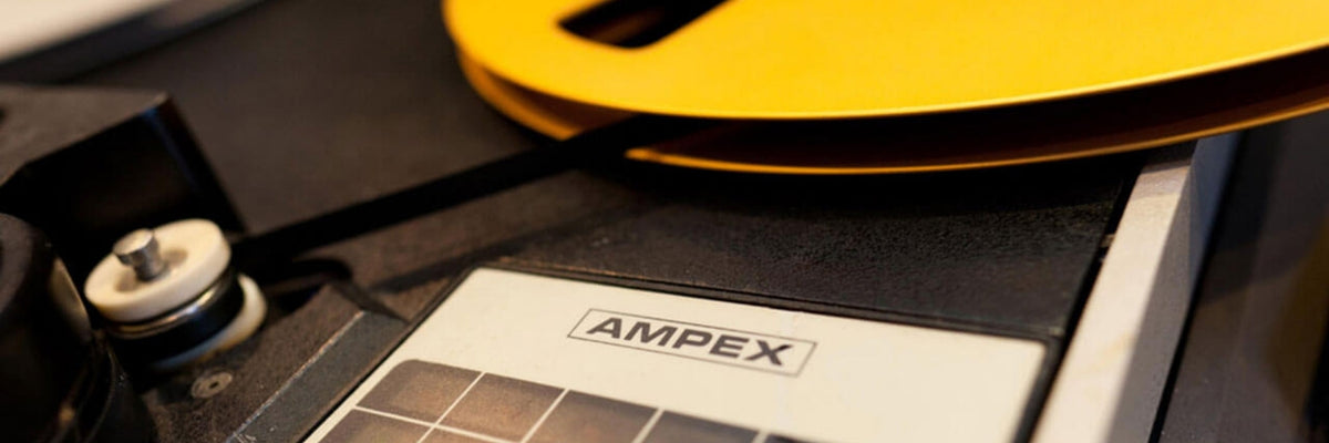 Close-up of an AMPEX device with a white label, black casing, and a bright yellow circular component in the background.