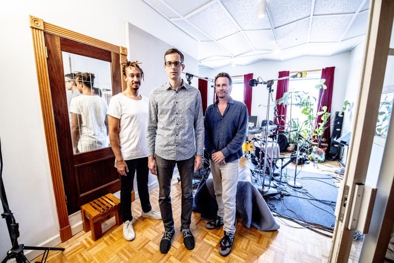 Matt Slocum Trio standing in front of a drum set and mirror.