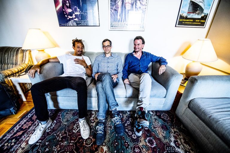 Matt Slocum and his trio sitting on a couch smiling.